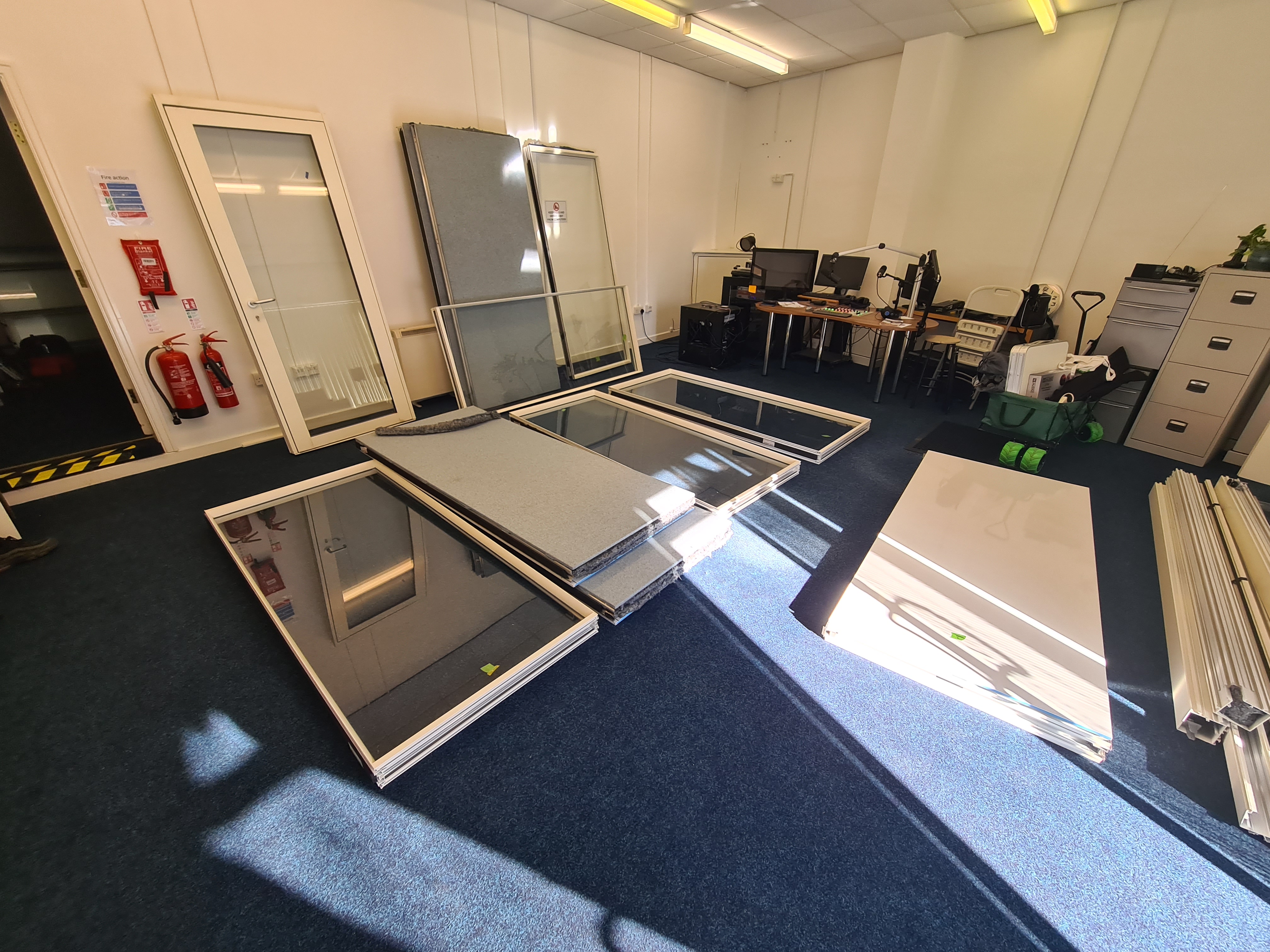 Glass panes and doors laid out in a room, ready for installation of a soundproofed booth
