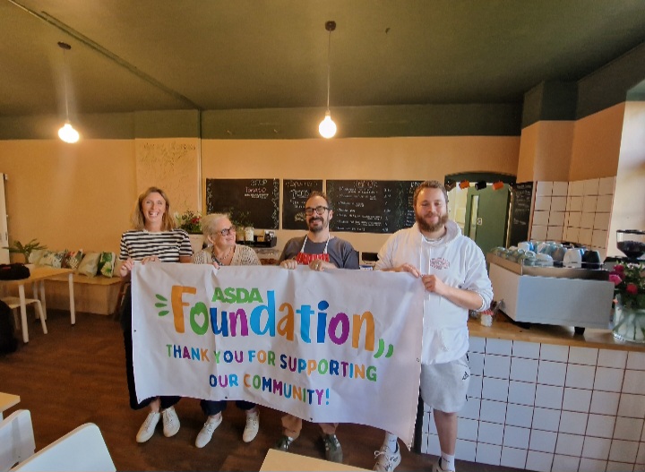 Group of people holding a banner for Asda Foundation to say thank you for their contribution.